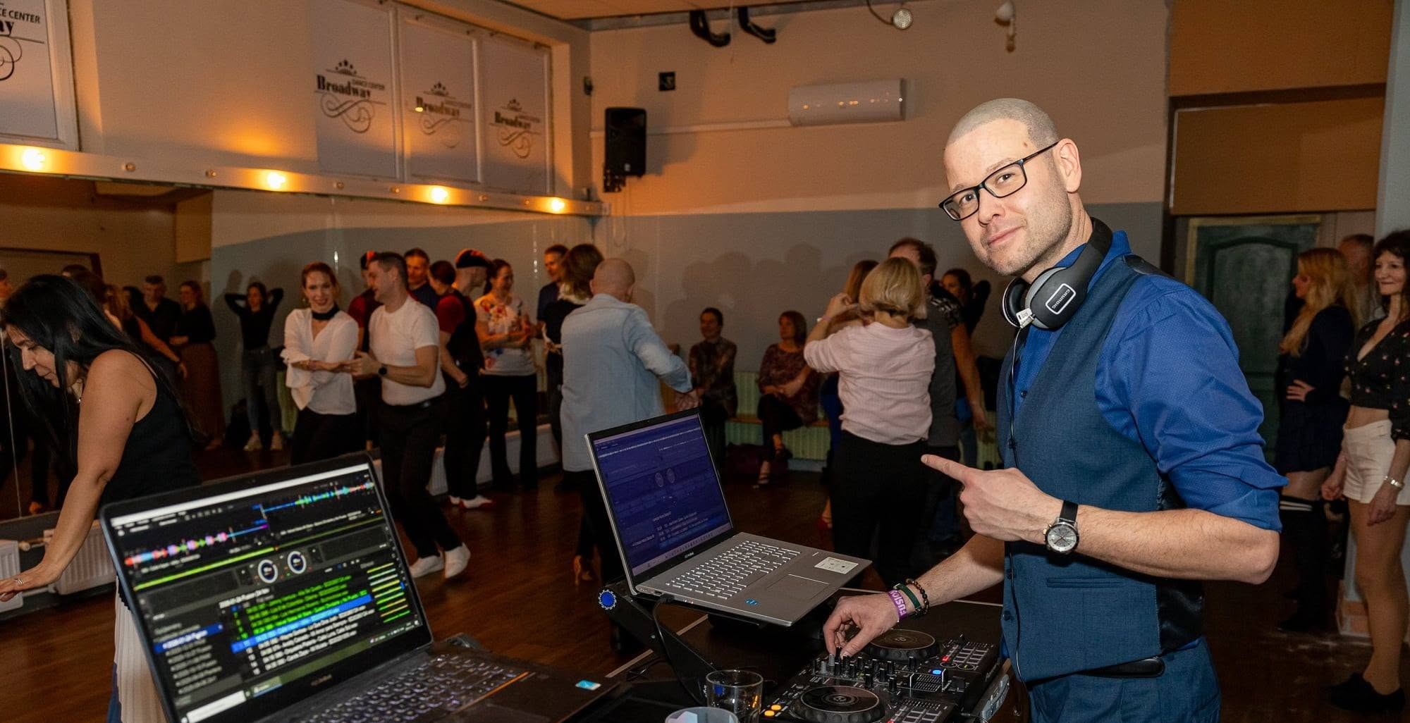 DJ Háros a pult mögött, táncoló vendégekkel a háttérben